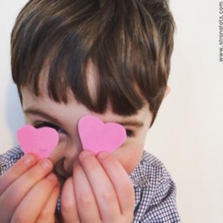 Boy holding hearts up in front of his face