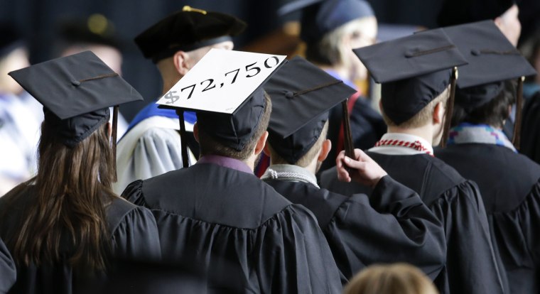 Image: A student in line for his diploma wears a cap decorated with the cost of his education during graduation ceremonies at the University of Idaho in Moscow, Idaho