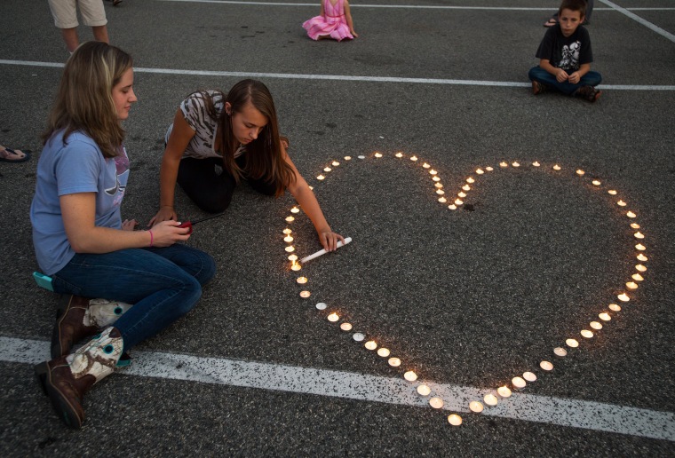 Image: Community supporters light candles in the shape of a heart during a vigil for the killed journalists