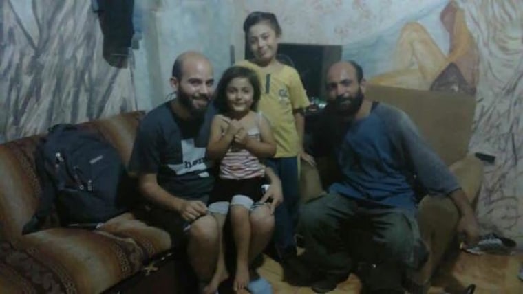 Image: Syria refugee Abdul (right), with son Abdelillah, 9, and daughter Reem, 4, and an activist