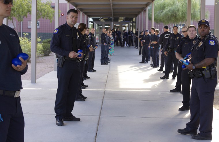Police officers and firefighters line up to greet the children of police officer killed in the line of duty in Phoenix, Arizona.