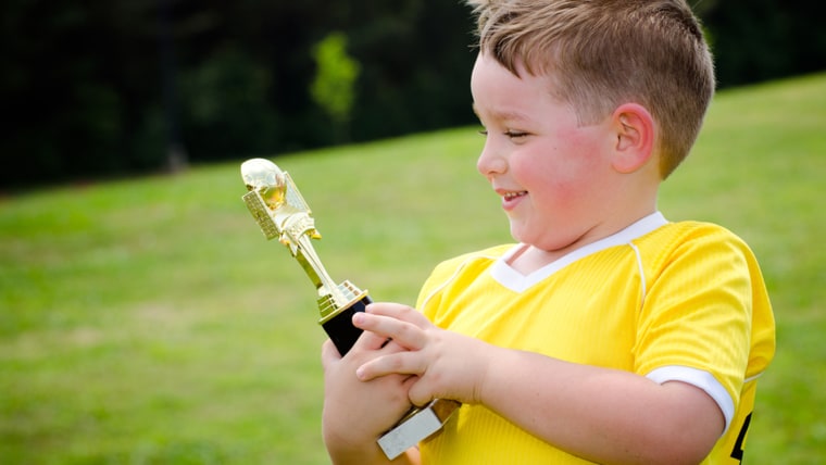 Young soccer player in uniform with his new trophy.