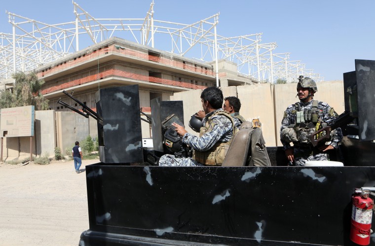 Image: Iraqi security forces guard the entrance to a sports complex