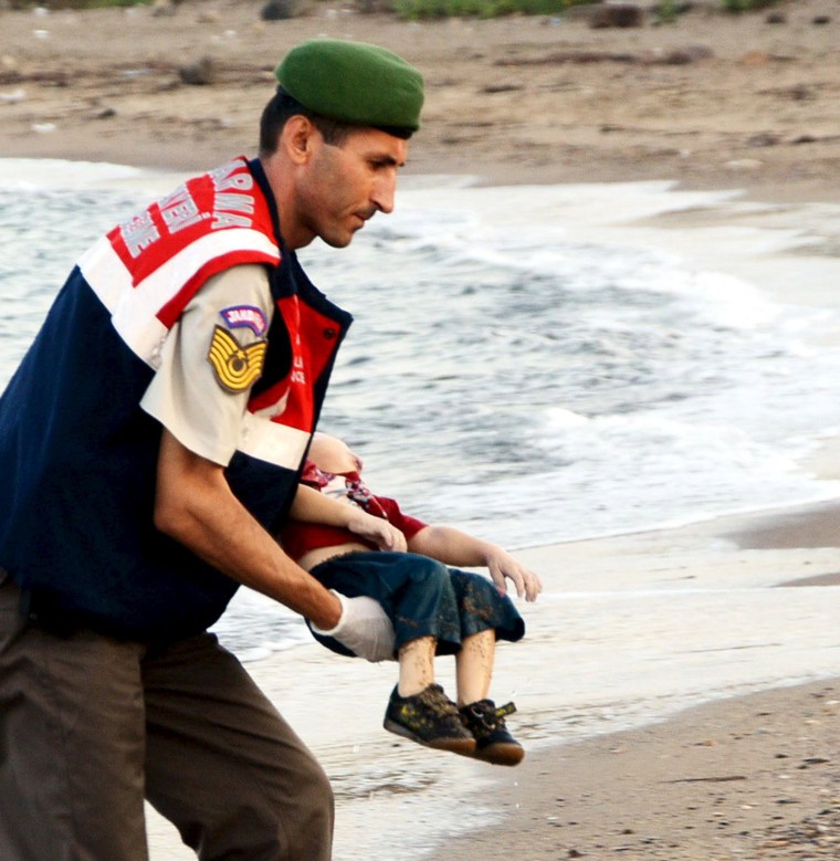 Image: A Turkish official carries a young migrant, who drowned in a failed attempt to sail to the Greek island of Kos