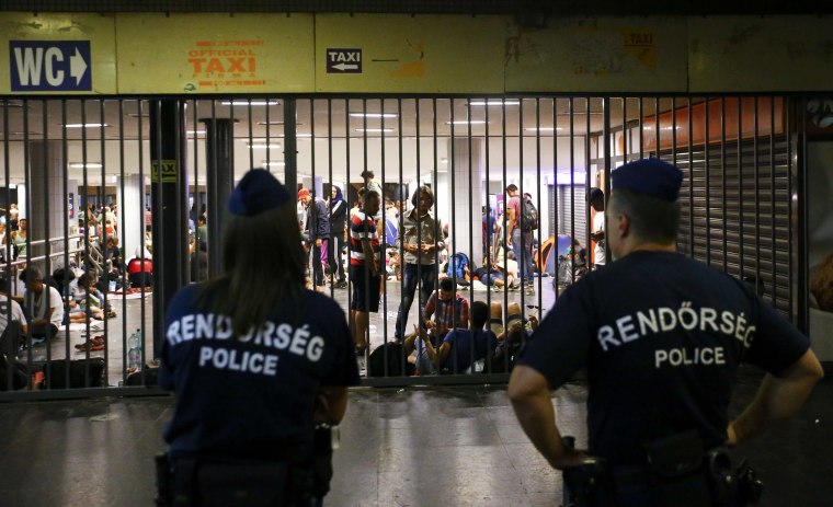 Image: Hungarian police guard refugees at a makeshift camp in an underground station near the Keleti train station in Budapest