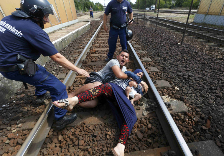Image: Hungarian police officers stand by migrants at the railway station in the town of Bicske
