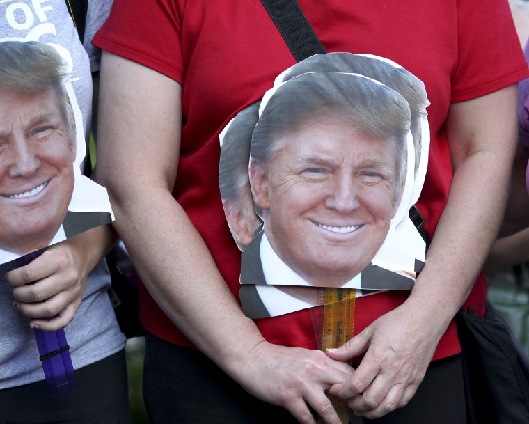 Image: A woman holds signs depicting the head of Republican presidential candidate businessman Donald Trump