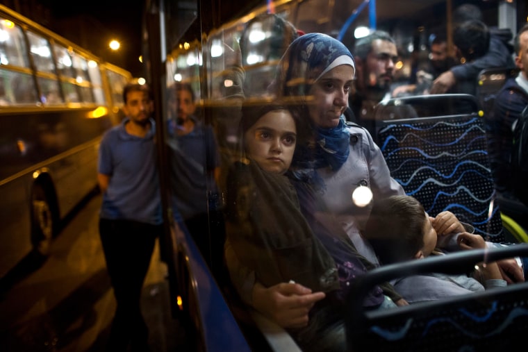 Image: A woman and her children sit as they have boarded a bus provided by Hungarian authorities