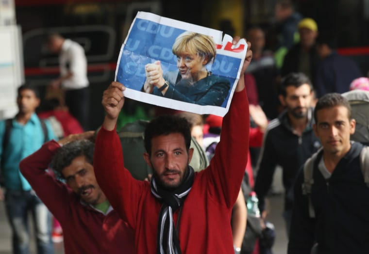 Image: A migrant arriving in Germany holds a picture of Angela Merkel