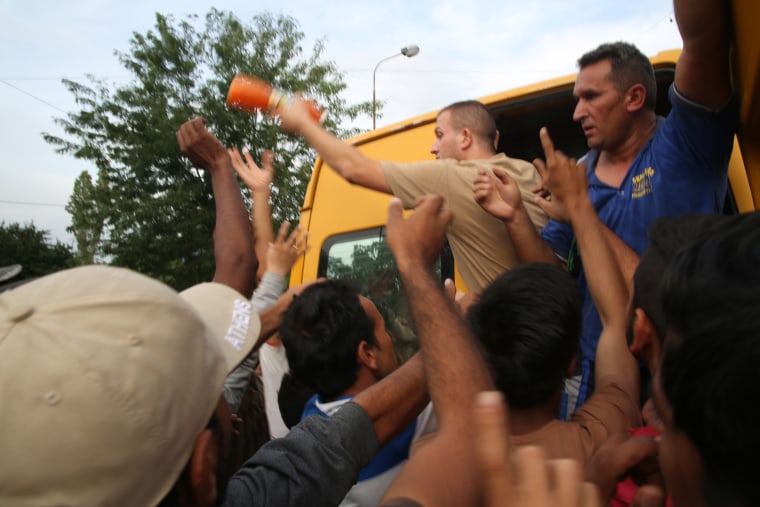 Image: Driton Redzepi (left) and Hajriz Musliu hand out water and juice to refugees
