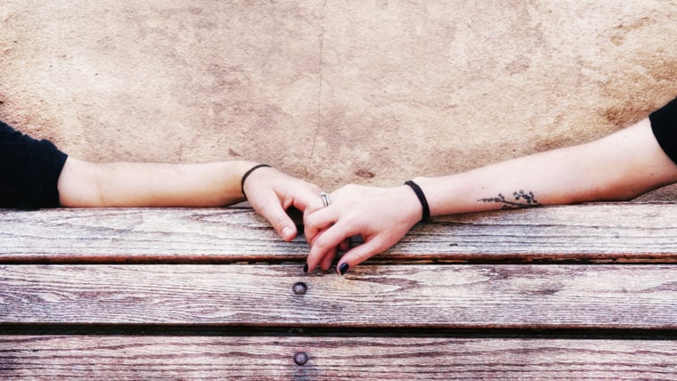 two people holding hands on a bench