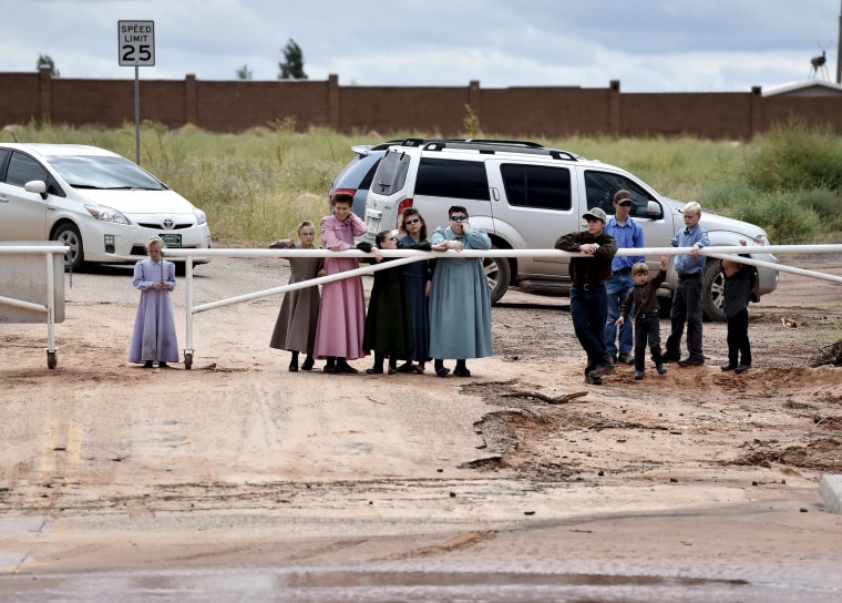 Image: Residents watch rescuers search along the Short Creek after a flash flood in Hildale, Utah