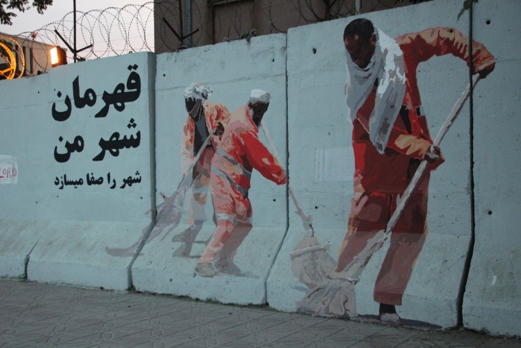 Image: A mural designed by Afghan artist Kabir Mokamel appears on a Kabul blast wall, depicting the city's street sweepers.