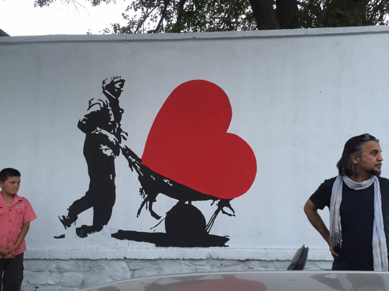 Image: Kabir Mokamel paints on a concrete blast wall