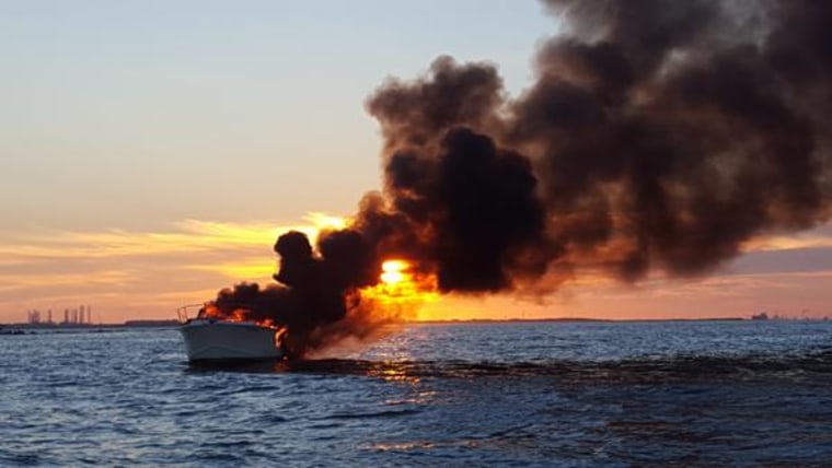 A yacht is seen on fire after four people were rescued by a boater in the waters near Galveston, Texas, on Saturday.