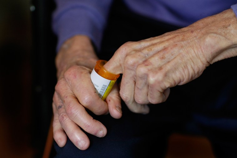 Image: A man reaches into a medicine bottle