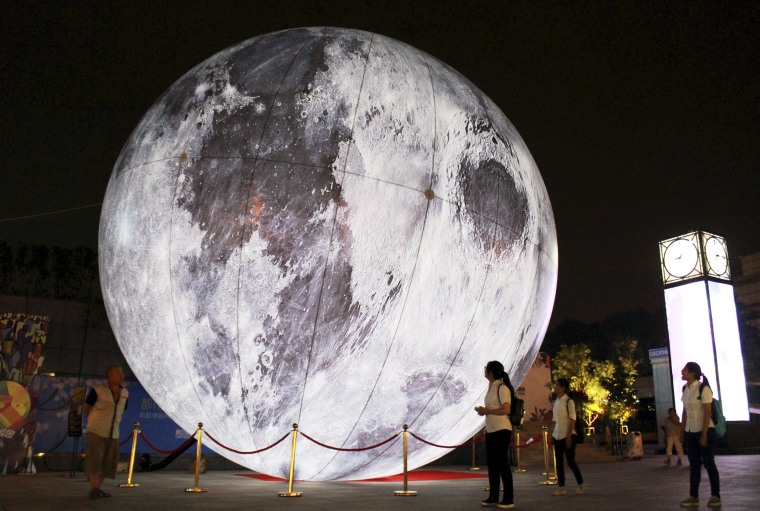 Image: Visitors look at a "moon" balloon on display ahead of the Mid-Autumn Festival at a square in Nanjing