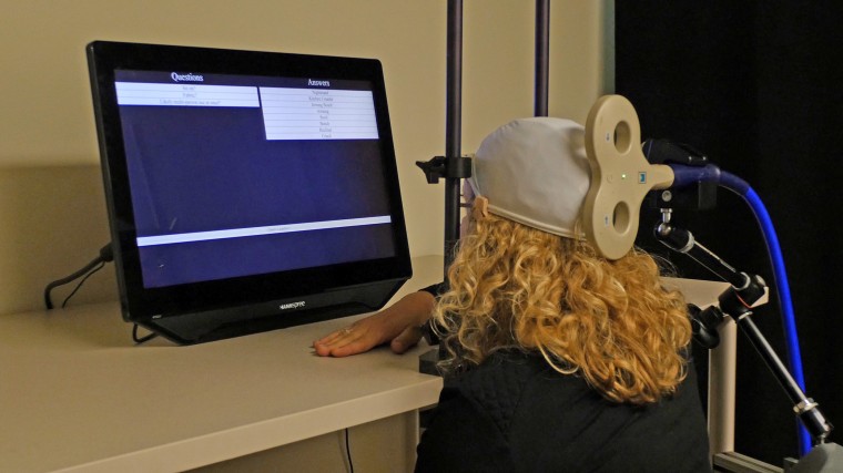 University of Washington postdoctoral student Caitlin Hudac, the “inquirer,” wears a cap that uses transcranial magnetic stimulation (TMG) to deliver brain signals from the other participant, the “respondent.”