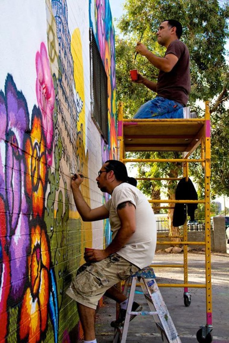 Artists Gennaro Garcia (top) and Hugo Medina (bottom) are seen here working together on the first mural of Calle 16, a mural project they helped co-found in 2010.