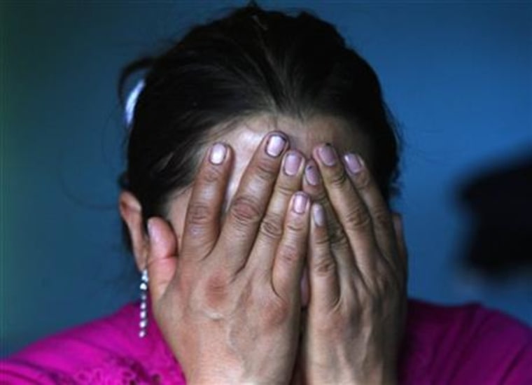 In this Aug. 8, 2015 photo, Afrodita Mondragon, mother of slain student Julio Cesar Mondragon, covers her face in grief as she speaks inside her home in San Miguel Tecomatlan, a rural town in the hills of Mexico state. Unlike the families of the 43 students who disappeared a year ago, Julio's loved ones were left with a body to bury. But there is little comfort in that, because his corpse bore witness to the horror of his final moments. His autopsy showed several skull fractures and other injuries and internal bleeding to his body consistent with torture. His face had been flayed, a tactic often used by the drug cartels to incite terror and send a message.