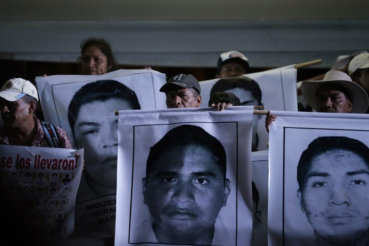 Image: Relatives of the 43 missing students of the Ayotzinapa teachers' training college hold pictures of the students, during a protest at Zocalo square in Mexico City