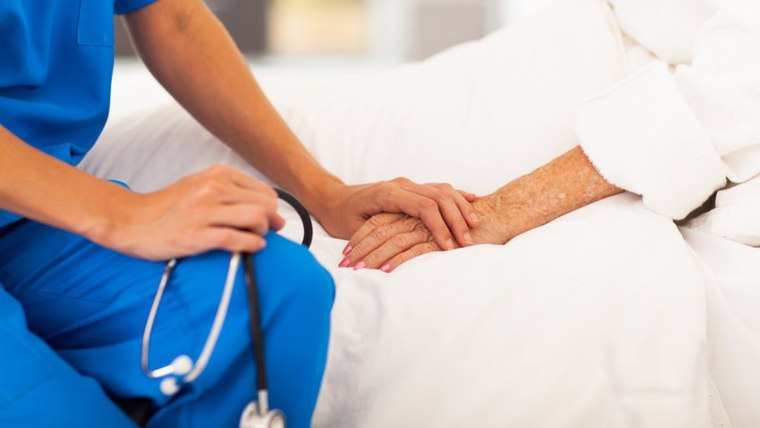 Nurse holds elderly patient's hand