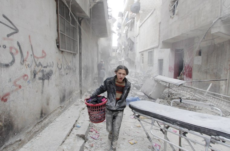 Image: A boy carries his belongings after alleged barrel bombing in Aleppo