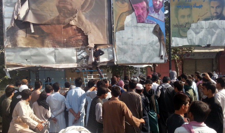 Image: A Taliban supporter removes leaders' pictures in Kunduz