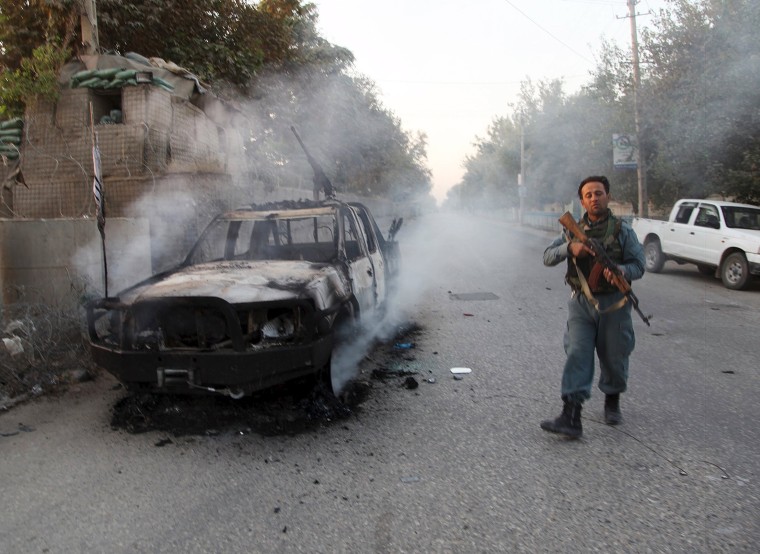 Image: An Afghan police officer patrols near burning car in Kunduz