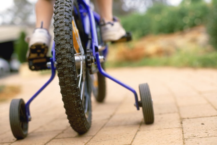 Photo: Child riding bicycle with training wheels.