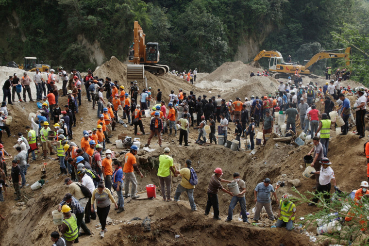 Image: Rescue team members and volunteers remove dirt with buckets from the site of a mudslide in Santa Catarina Pinula