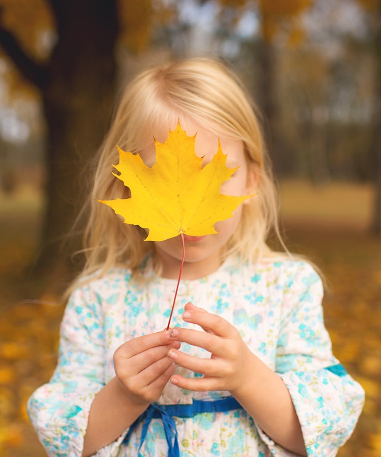 Allowing your child to find the biggest leaf she can, then hide her face behind it is one of Wilkerson's suggestions for interesting leaf pile photos.