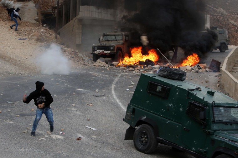 Image: A protester throws a bottle at Israeli security forces vehicles