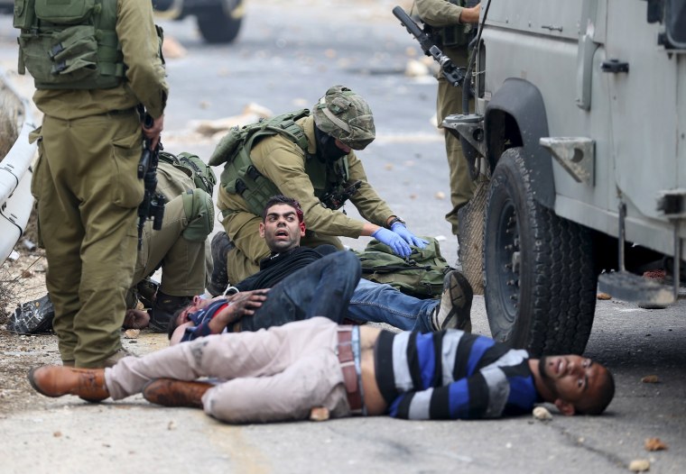 Image: Israeli soldiers detain wounded protesters in West Bank