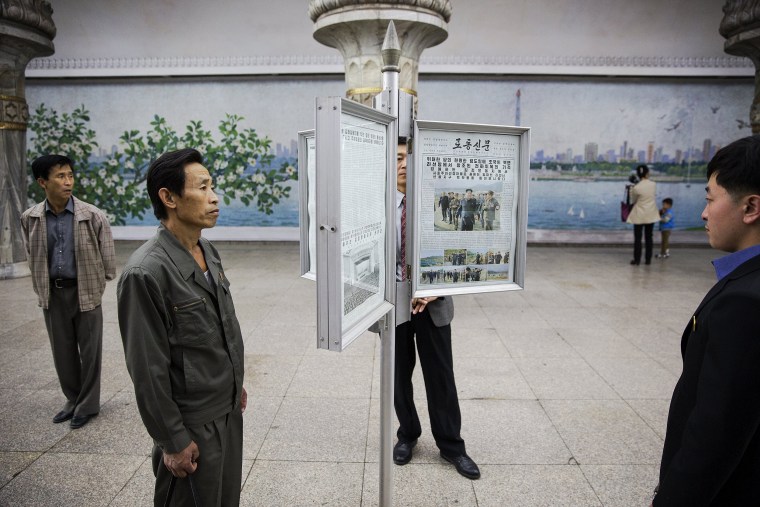 Image: People read newspapers displayed inside a subway station visited by foreign reporters during a government organised tour in Pyongyang