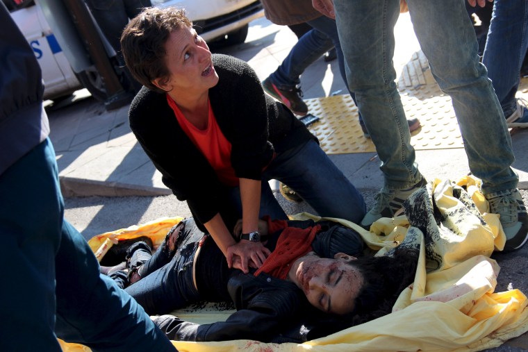 Image: A woman helps an injured woman after an explosion during a peace march in Ankara