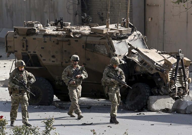 Image: NATO soldiers walk in front of a damaged NATO military vehicle at the site of a suicide car bomb blast in Kabul