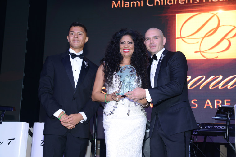 Nicholas Lopez-Morillo and Lucy Morillo, President and CEO, Miami Children's Health Foundation present an award to Armando Christian Perez.