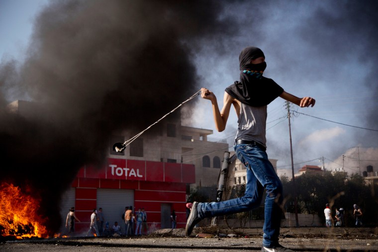 Image: A Palestinian hurls a stone during clashes with Israeli troops near Ramallah