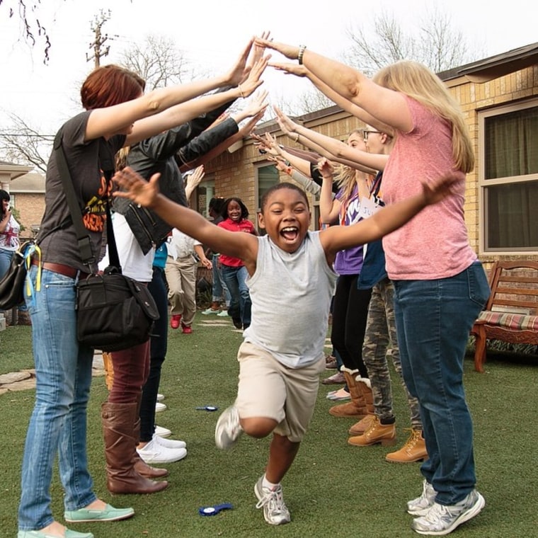 A young boy excitedly runs through a tunnel of people at his birthday party.