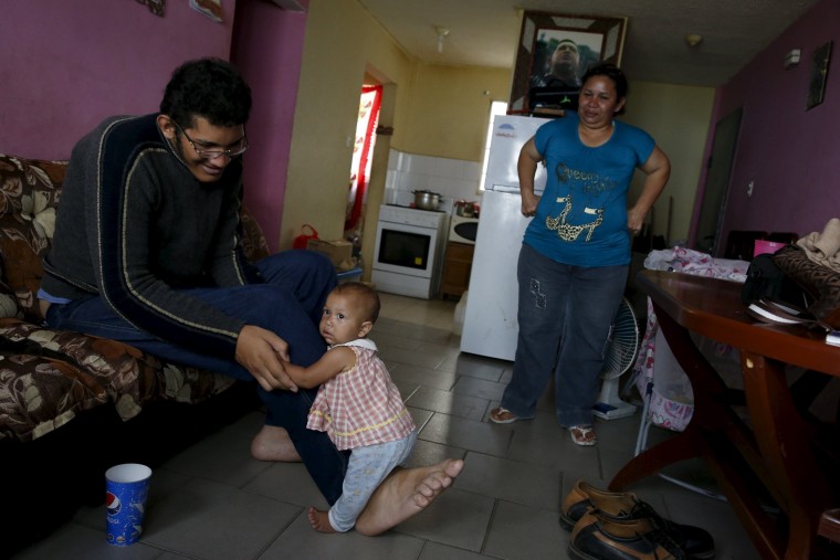 Image: Jeison Rodriguez (L), 19, the living person with the largest feet in the world, holds his niece Osmariel with the help of his foot at his house in Maracay, Venezuela