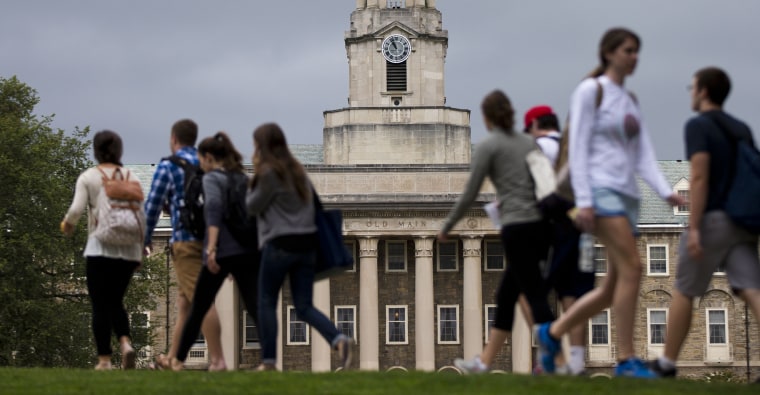 Students walk past the Old Main building on the Penn State campus Tuesday, Sept. 9, 2014, in State College, Pa. 