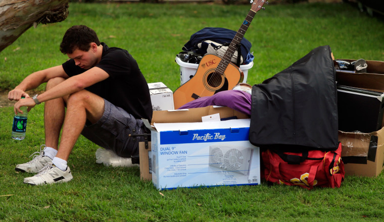 Image: A freshman waits with his belongings for his family to arrive to help him move into his dorm