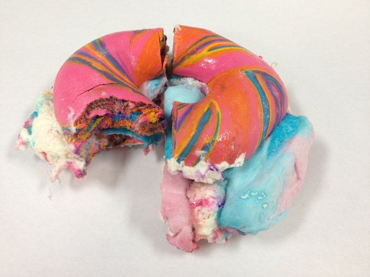 First bite of Rainbow Bagel Stuffed with Funfetti Cream Cheese and Cotton Candy from Brooklyn's The Bagel Store