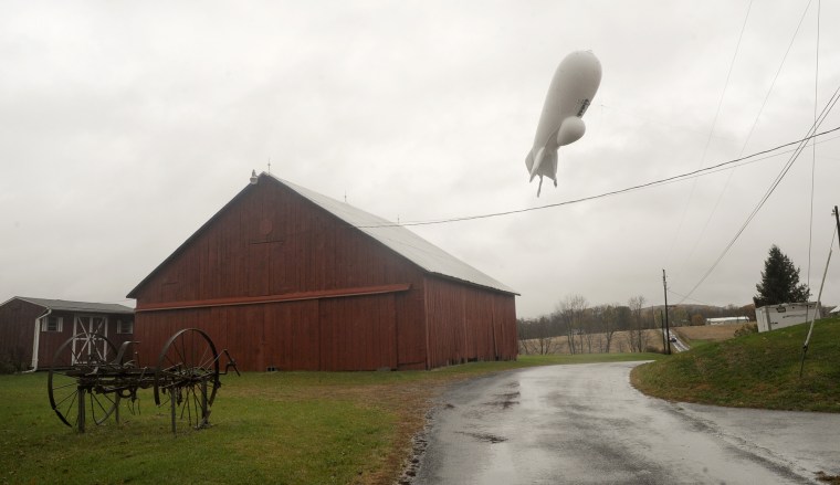 An unmanned Army surveillance blimp floats through the air while dragging a tether line south of Millville, Pa.