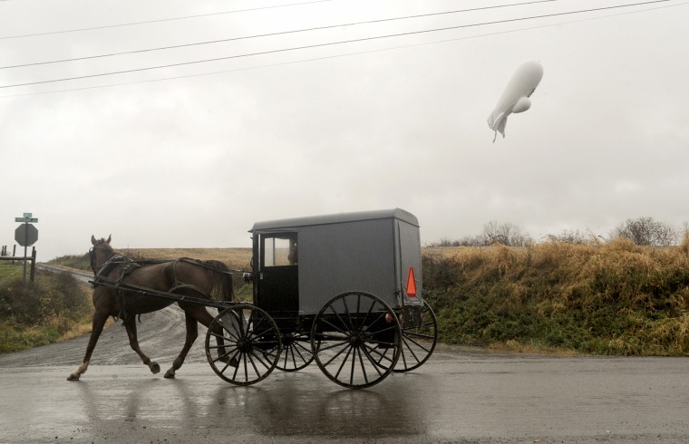 An unmanned Army surveillance blimp floats about 1,000 feet above ground while dragging a several thousand-foot tether line south of Millville, Pennsylvania, after it broke loose from its ground tether Wednesday in Maryland.