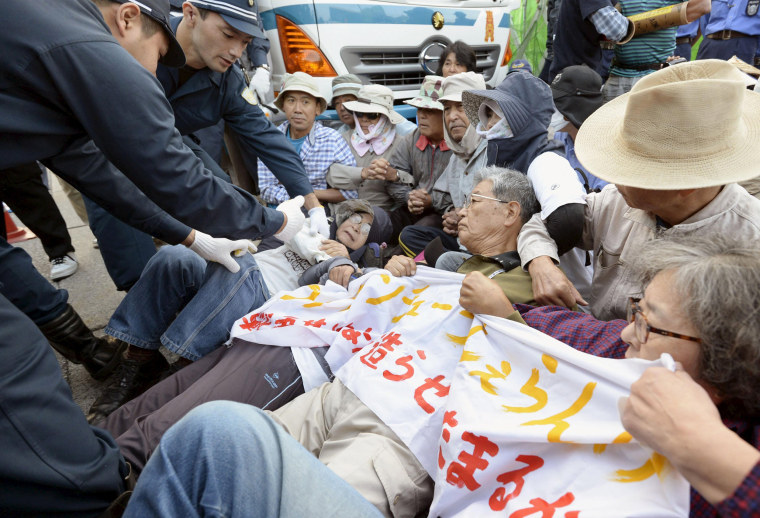 Image: Protesters lie on the ground as they try to block work on a contentious U.S. air base