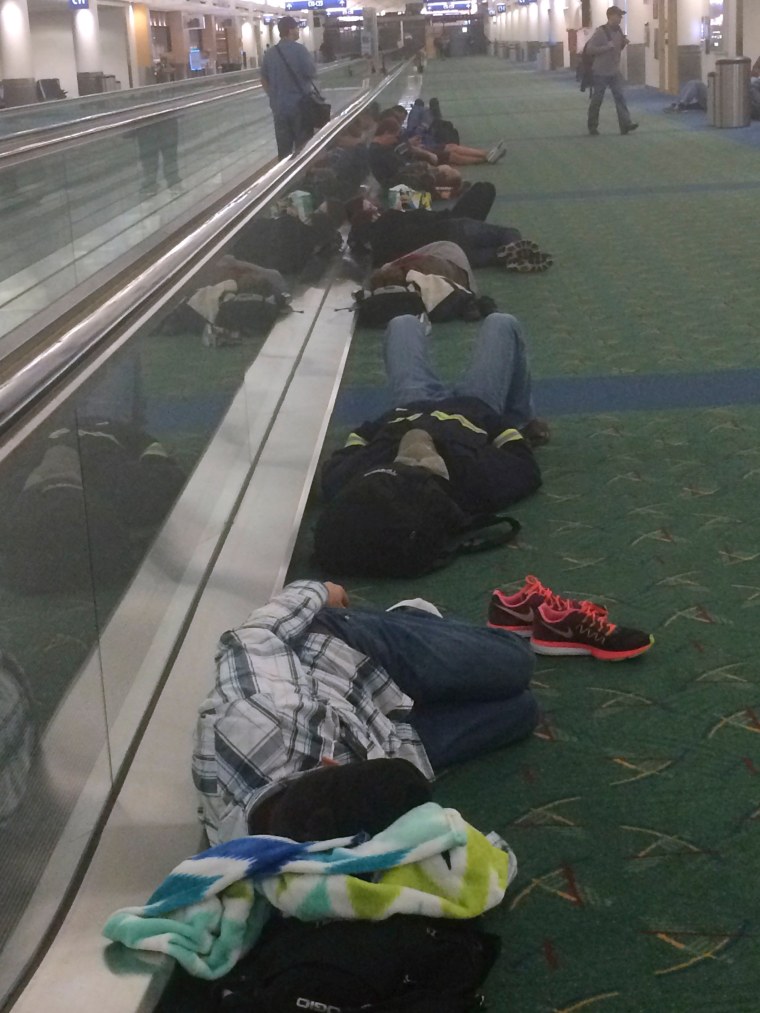 Image: Travelers sleep at Portland International Airport