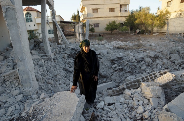 Image: A woman inspects a damaged site in Nawa city