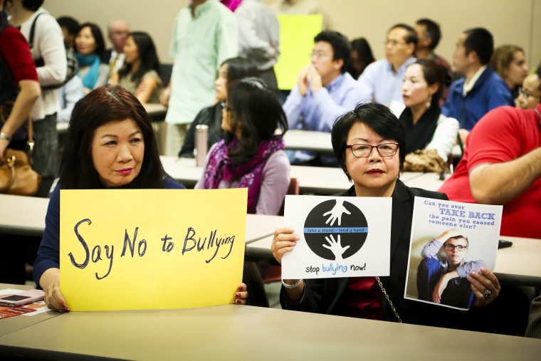 Louisa Luk and Gail Young hold signs against bullying during the Fairfield School Board meeting Thursday, Oct. 15, 2015, in Fairfield, Ohio. A large crowd was present to protest the ongoing bullying at Fairfield Middle School and the lack of action by administrators.